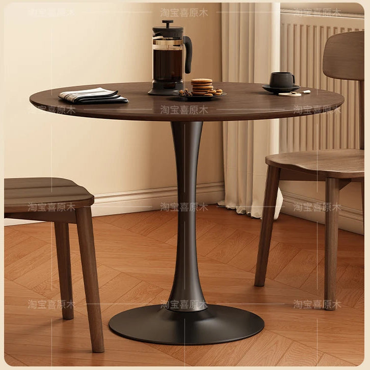Round wooden table with black metal base in a room setting